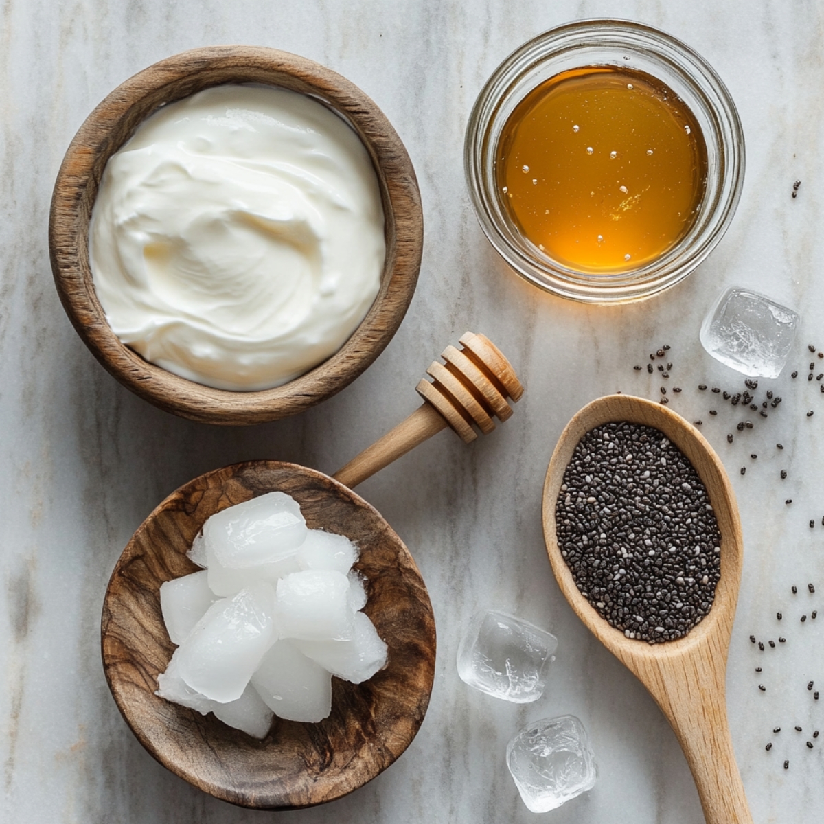 Greek yogurt, honey, chia seeds, and ice cubes arranged neatly on a marble surface with a cozy, homemade feel.