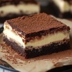Homemade tiramisu brownies with rich chocolate layers, creamy mascarpone filling, and a dusting of cocoa powder on top, served on parchment paper with a rustic, cozy feel.