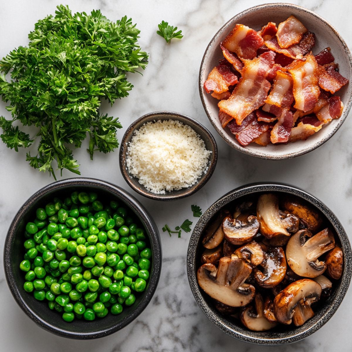 Fresh parsley, crispy bacon, grated cheese, green peas, and sautéed mushrooms in bowls on a marble countertop.