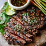 Grilled Steak Marinade, sliced and glazed with herbs, served on a wooden board with dipping sauce, lime, cilantro, and grilled vegetables.