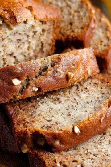 Homemade Banana Bread Recipe slices on a wooden board, with a golden crust, moist texture, and visible banana and nut pieces.
