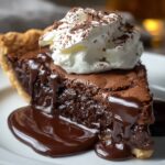 A decadent slice of chocolate pie on a white plate, its rich, fudgy filling dripping onto the plate, crowned with a swirl of whipped cream and delicate chocolate shavings.