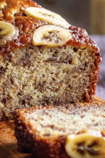 Homemade Banana Bread Recipe slices on a wooden board, with a golden crust, moist texture, and visible banana and nut pieces.