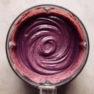 A blender filled with a smooth, creamy purple acai mix, swirling in the container.