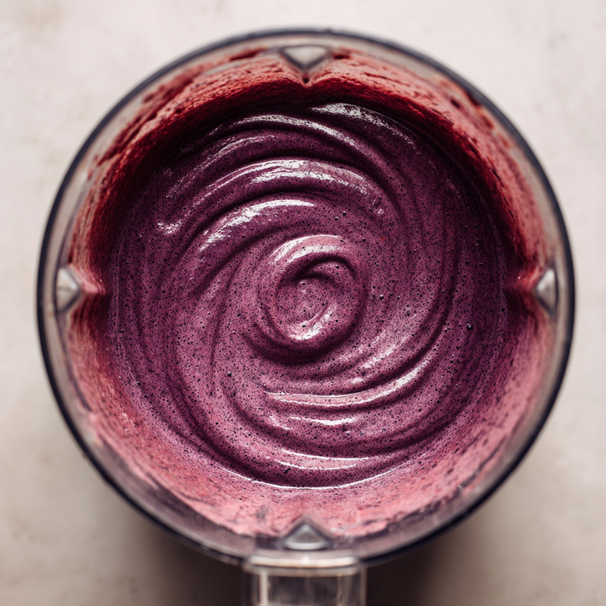 A blender filled with a smooth, creamy purple acai mix, swirling in the container.