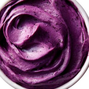 A close-up of smooth, purple acai bowl contents, showing its rich, velvety texture.