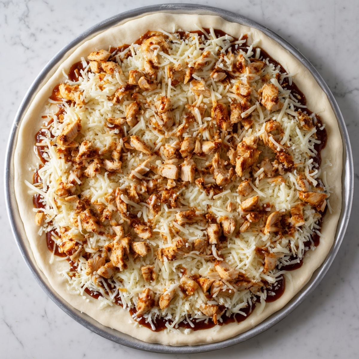 Pizza raw mghatta b jibna mozzarella w BBQ chicken mshat 3la dough.