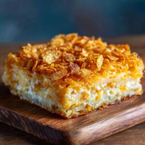White baking dish filled evenly with a creamy blend of shredded potatoes, sour cream, cream of chicken soup, and cheddar on a marble surface.