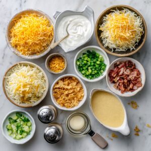Overhead on a marble counter: bowls of frozen hashbrowns, sour cream, cream of chicken soup, melted butter, diced onion, shredded cheddar, crushed cornflakes, chopped bacon, sliced green onions, and salt & pepper shakers.