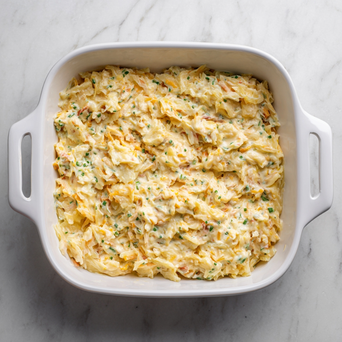 Close-up of a spoon lifting a portion of casserole, revealing the soft, cheesy potato interior beneath a crunchy cornflake topping.