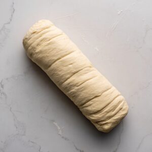 The dough rectangle slathered with creamy white cheese and sprinkled with coarsely crumbled sausage