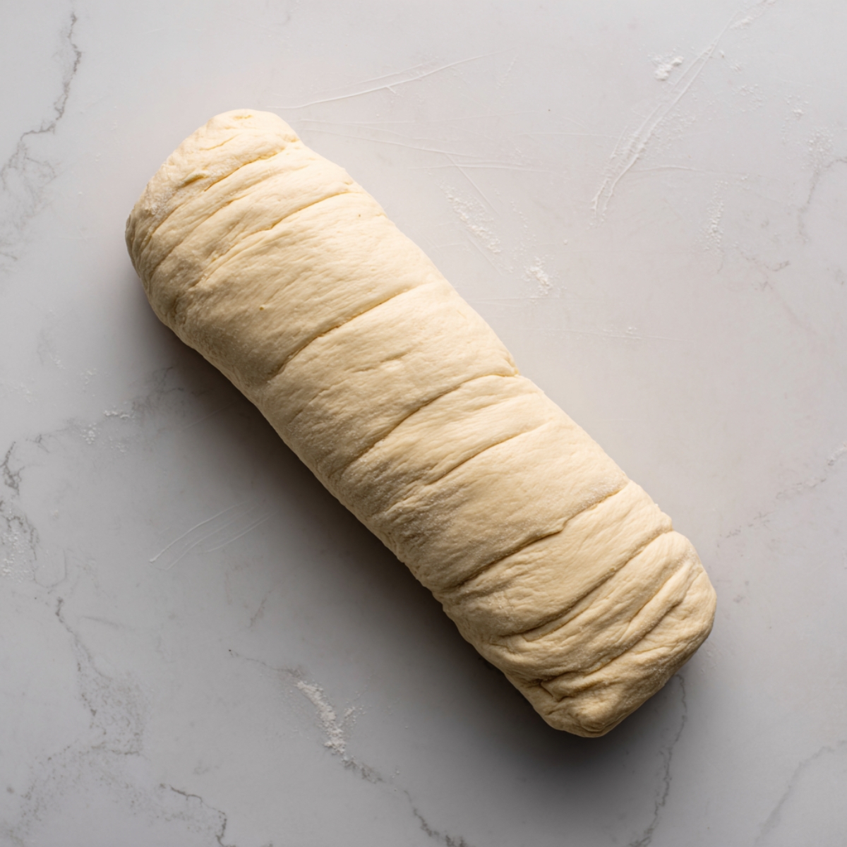 The dough rectangle slathered with creamy white cheese and sprinkled with coarsely crumbled sausage