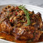 Braised Turkey Neck Recipe served in a deep white bowl with rich sauce, garnished with rosemary and fresh herbs.