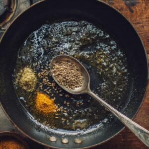 Golden chickpeas being added into a simmering creamy tikka masala sauce with steam rising.