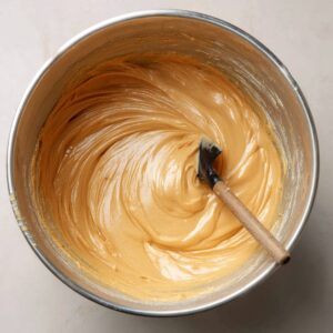 Smooth honey cake batter in a stainless steel bowl with a spatula, ready to be portioned and baked.
