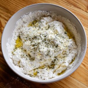 Bowl of flour mixture combined with shredded cheese, herbs, and olive oil, ready to be mixed