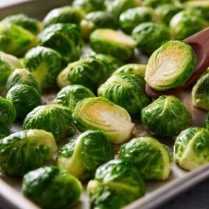 Halved roasted Brussels sprouts on a baking sheet, caramelized edges, seasoned with salt and pepper.