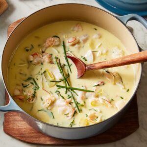 Creamy fish chowder with chunks of fish and green herbs, served with baguette bread and olive oil on the side.