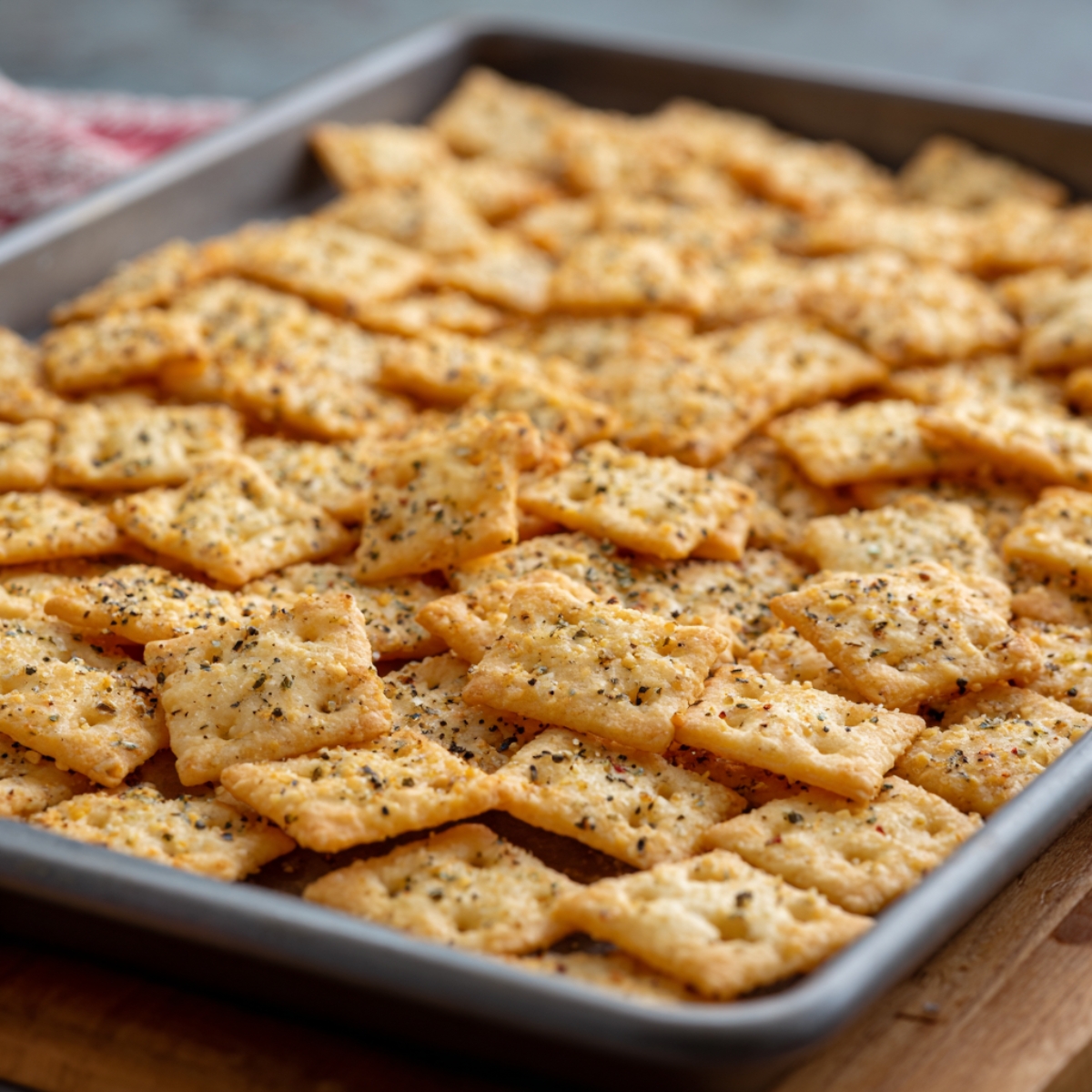 A baking sheet covered with a single layer of seasoned crackers, ready for baking.