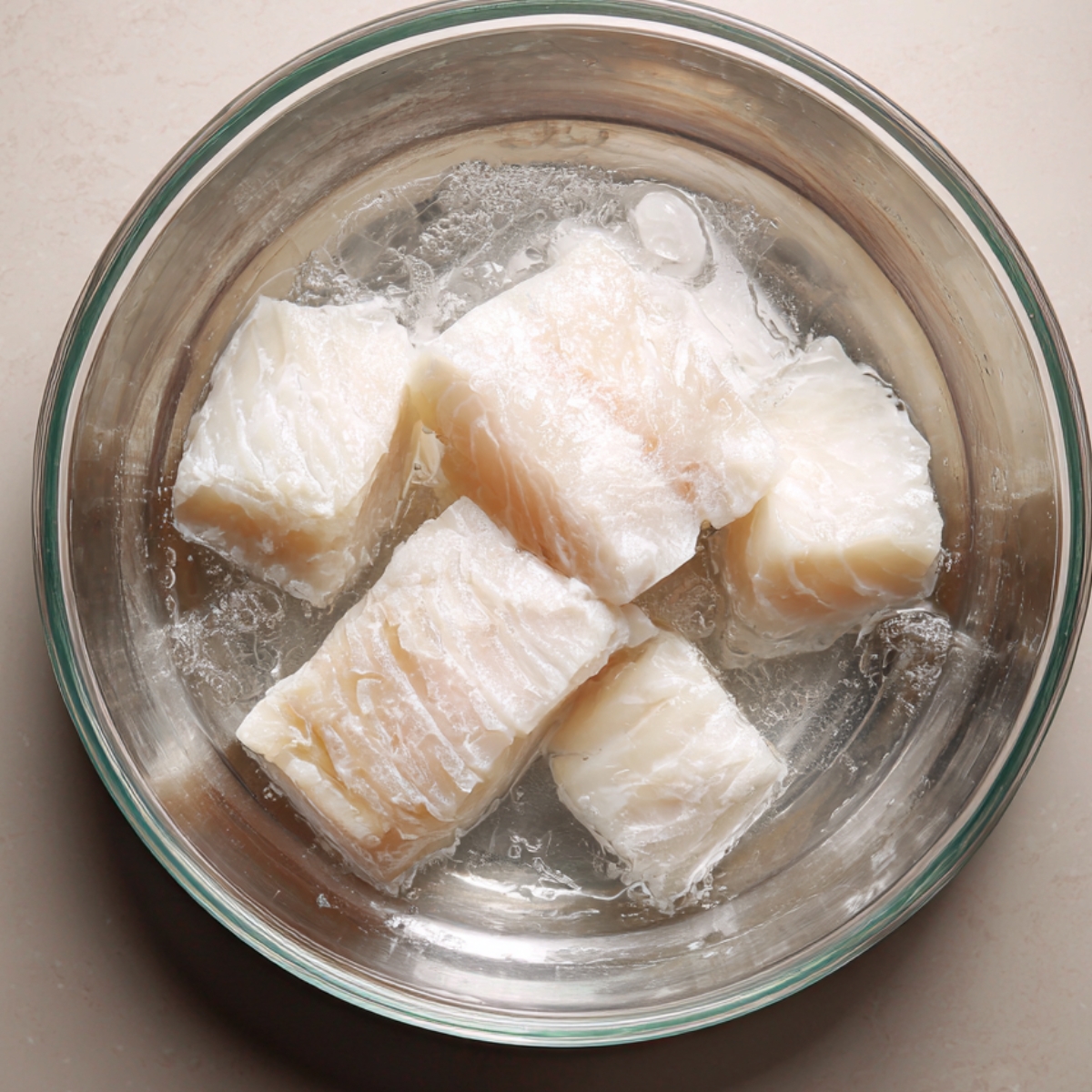 Salted cod being soaked in water to remove excess salt.