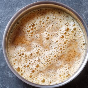 A foamy yeast mixture resting in a metal bowl after activation.