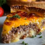Plated cheeseburger pie slice: A rich, gooey slice of cheeseburger pie served on a plate, showing melted cheese and beef layers with a flaky crust.