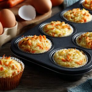 Carrot cupcake preparation: Fresh ingredients (carrots, eggs, batter) with partially baked carrot cupcakes in muffin liners.