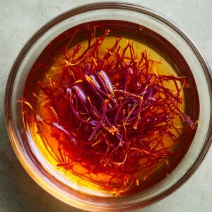 Crush saffron threads gently between your fingers and drop them into hot water. Let it sit for 10-15 minutes to release its deep color and aroma.