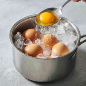 A small saucepan with sesame oil, soy sauce, and ginger being mixed to create a base for the ramen broth.