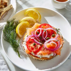 Everything bagel with cream cheese, smoked salmon, sliced tomatoes, red onions, capers, and fresh dill, served with lemon wedges and tea.