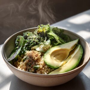 Steaming bowl of quinoa with sliced avocado, sautéed greens, and sprinkled herbs, served in natural light on a minimalist table.