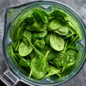 Fresh baby spinach leaves packed into a blender to make a nutrient-rich spinach puree.