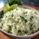 Cilantro Lime Rice A close-up bowl of cilantro lime rice, garnished with fresh cilantro and served with lime wedges on the side.