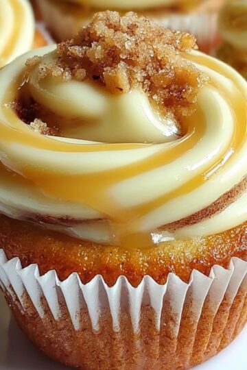 Cinnamon Roll Cupcakes topped with cream cheese frosting, brown sugar crumble, and a drizzle of caramel sauce.