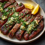 Cowboy Butter Steak on a white plate, topped with melting herb butter and chopped parsley, garnished with lemon wedges.