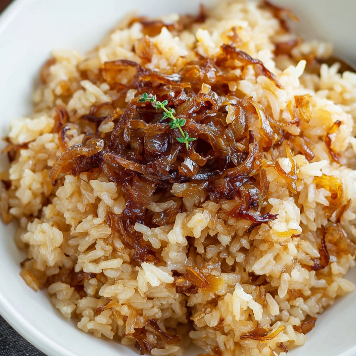 French Onion Butter Rice A white bowl of French onion butter rice, featuring a mound of caramelized onions in the center and a spoon to the side.