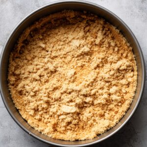 Pressed graham cracker crust in a round springform pan, ready for cheesecake filling.
