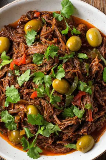 Delicious Cuban Ropa Vieja Recipe 22 Cuban Ropa Vieja Another shot of the final Cuban Ropa Vieja dish, beautifully garnished with fresh cilantro, green olives, and red peppers, making it look both delicious and appetizing.