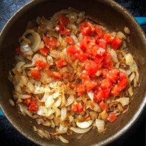 Easy Chicken Paprikash Recipe | Traditional Hungarian 16 Sauteed onions cooked with diced tomatoes, garlic, and paprika spices in a pot, preparing the base for chicken paprikash sauce