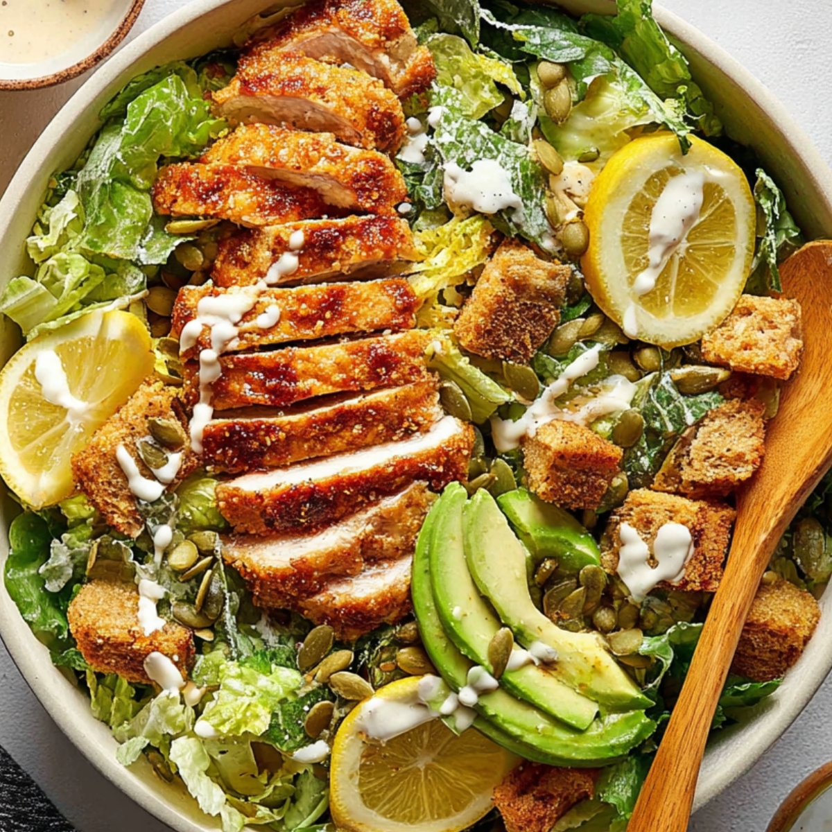 Honey Hot Chicken Salad Recipe | Crispy & Spicy in 30 Min 9 Honey Hot Chicken Salad Finished hot honey chicken Caesar salad with sliced crispy chicken, romaine lettuce, croutons, avocado slices, pumpkin seeds, lemon wedges, and creamy dressing in a large bowl.