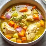 Jamaican chicken soup Bowl of hearty chicken soup with carrots, potatoes, onions, whole peppercorns, and seasoned broth served warm.