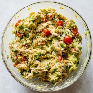Healthy Avocado Chicken Wrap Recipe | 10-Minute Lunch 16 Avocado chicken mixture in a glass bowl with shredded chicken, mashed avocado, cherry tomatoes, and fresh herbs, photographed from an overhead view.