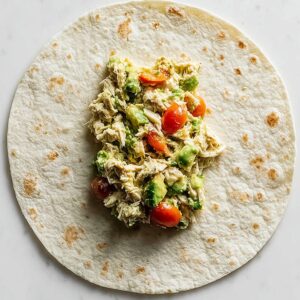Healthy Avocado Chicken Wrap Recipe | 10-Minute Lunch 17 Avocado chicken wrap filling placed in the center of a flour tortilla, showing the wrap assembly step from an overhead perspective.