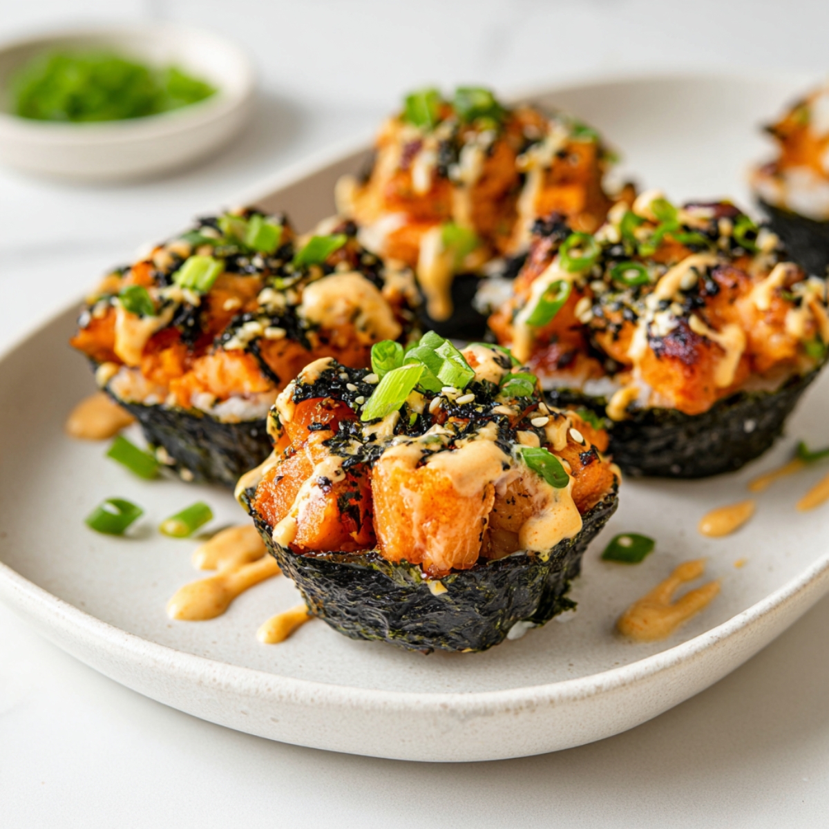 Easy Baked Salmon Sushi Cups | 30-Minute Recipe 13 Crispy baked salmon sushi cups on a white plate, nori seaweed cups filled with rice and roasted salmon, topped with spicy mayo and green onions