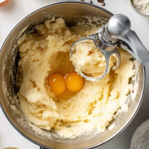 Boston Cream Pie Cookies Recipe | Easy & Delicious 17 “Overhead shot of cookie dough being mixed in a stand mixer bowl with eggs and vanilla added, surrounded by baking ingredients, bright natural kitchen lighting, professional food photography”