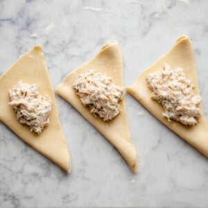 Healthy Chicken Pillows Recipe | Ready in 30 Minutes 17 Crescent roll triangles filled with creamy chicken mixture, laid out before rolling and sealing.