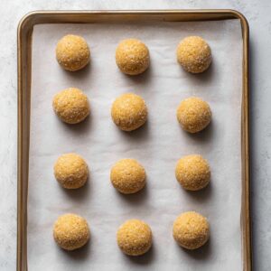 Easy Honey Cookies Recipe - Chewy, Spiced & Foolproof 19 Nine unbaked honey cookie dough balls, rolled in sugar and spaced evenly on a parchment-lined baking sheet.