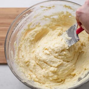 The Best Irish Potato Pancakes Recipe 16 "A person mixing boxty pancake batter in a clear mixing bowl using a spatula. The thick, creamy batter is ready to be cooked."