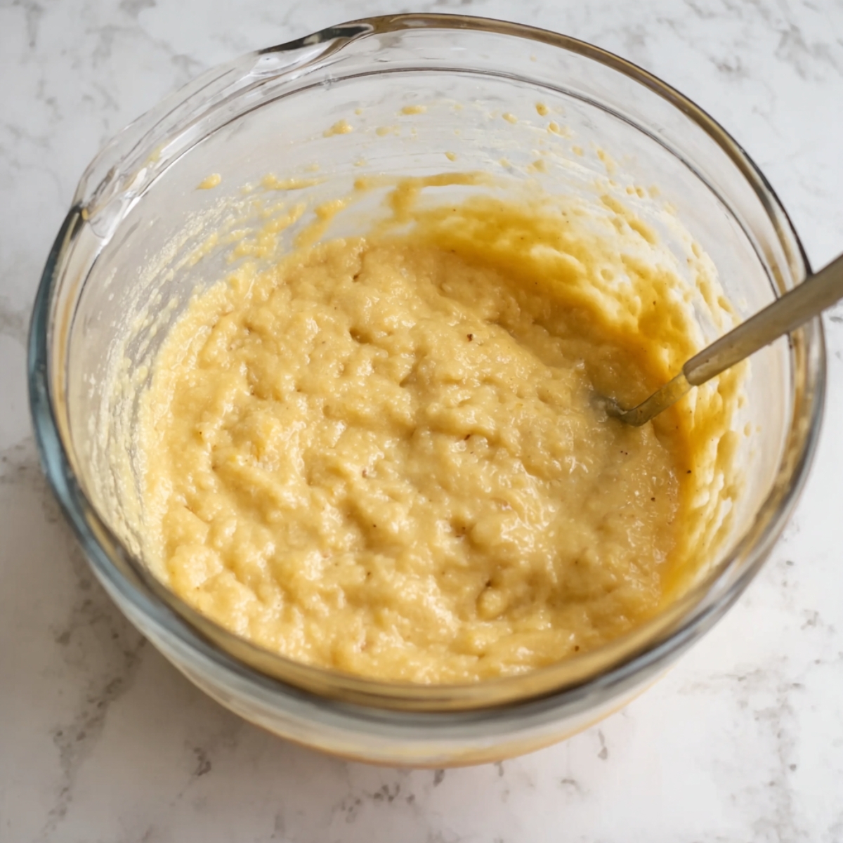 Easy Jamaican Banana Fritters Recipe | Ready in 15 Min 10 Another view of banana fritter batter in a mixing bowl, with a spoon stirring the thick, smooth batter.
