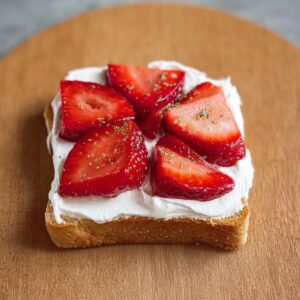 Japanese Fruit Sandwich Recipe (Ready in 10 Minutes!) 16 "A slice of soft bread topped with freshly whipped cream and sweet, ripe strawberries, creating a perfect base for a simple treat."